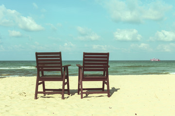 Fototapeta na wymiar two wooden chairs on the beach, bright vintage filter wallpaper
