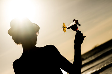 silhouette of young woman with glass of tropical cocktail on sun