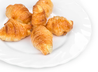 Fresh croissants on white plate.