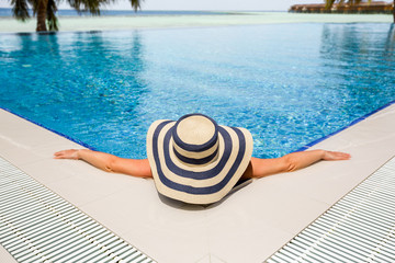 Obraz premium Woman in straw hat relaxing swimming pool
