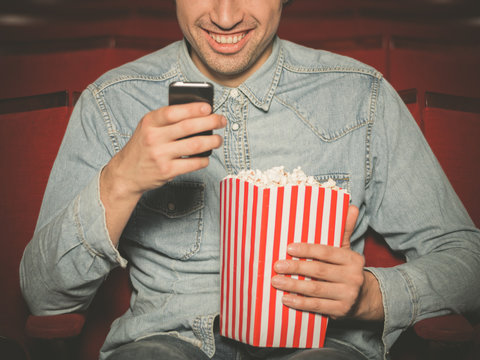 Young man using his phone at the cinema