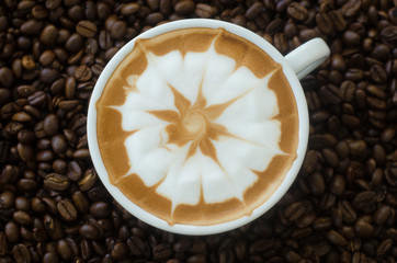 a cup of latte art on coffee bean background