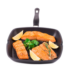 Fried salmon fillet in pan with lemon.