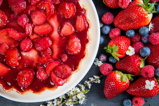 overhead view on fresh strawberry pie with berries fruit on side