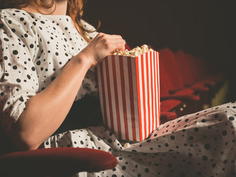 Young woman eating popcorn in movie theater