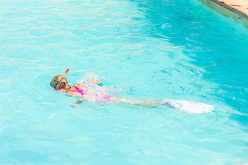 little girl snorkeling in swimming pool