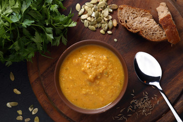 Pumpkin and lentil soup, bread and green on the wooden board
