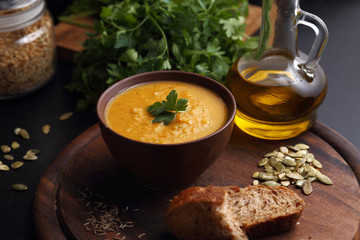 Pumpkin and carrot soup, bread and green on the wooden board