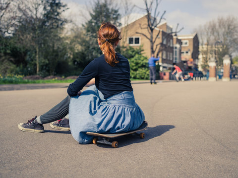 Woman sitting on skateboard in the park