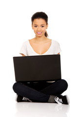 Teen sitting cross legged with laptop.