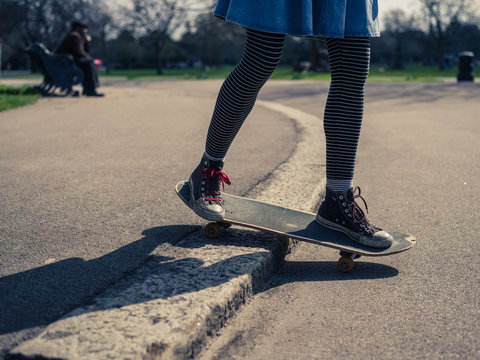Young woman doing skateboard trick on curb