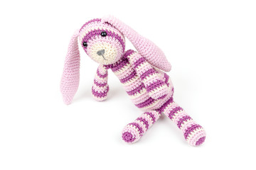 Knitted rabbit toy is sitting isolated on white