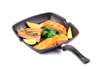 Fried salmon fillet in pan with lemon.