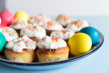 small cakes and colored Easter eggs on plate side view