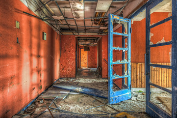 Blue door in red dilapdated corridor at an abandoned hotel