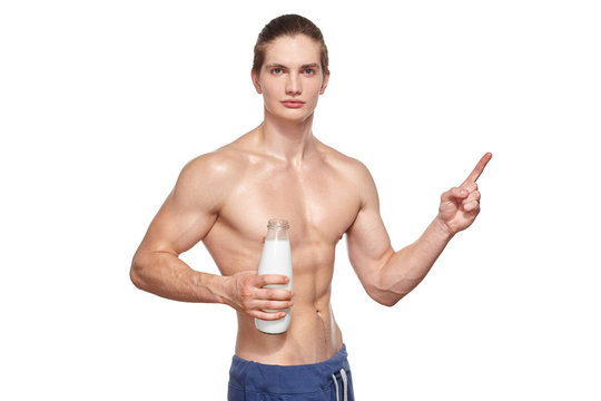 Handsome young muscular athlete holding bottle of milk