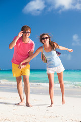 front view of happy couple in sunglasses on the beach