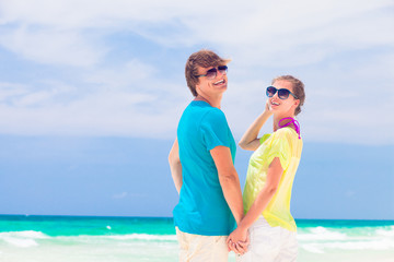 back view of happy couple in sunglasses on the beach