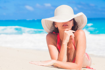 woman in bikini and straw hat relaxing on tropical beach