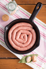 Raw chiken sausage in a cast-iron frying pan.