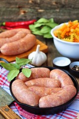 raw chicken sausages with vegetables on a frying pan