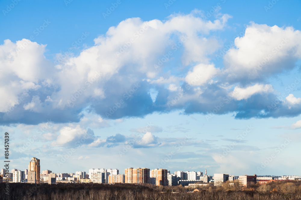 Wall mural clouds in blue spring sky over city