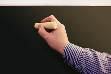Close up of male hand writing on a blackboard