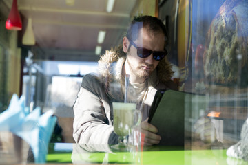 Russian man with beard sitting inside a cafe in glasses
