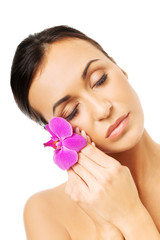 Naked woman with purple orchid petal near face