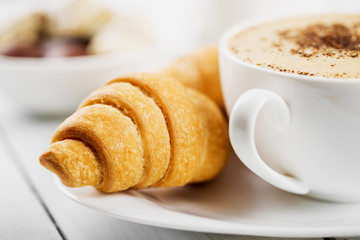 Hot cappuccino and pastries on white wooden boards