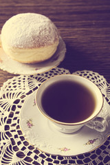 Doughnut with cup of tea in old-fashioned room on napkin