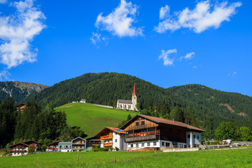 Green meadow and alpine houses in Strassen village, Austria