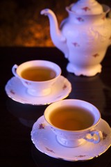 Old-style kettle with two cups of tea on black