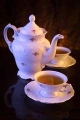 Old-style kettle with two cups of tea on black