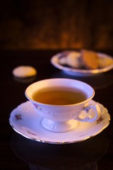 Old-style image cup of tea with cookies on black