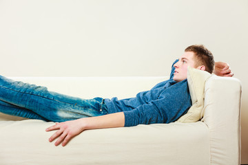 Young pensive man relaxing on couch