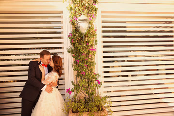Bridal couple holding each other next to vintage blinds