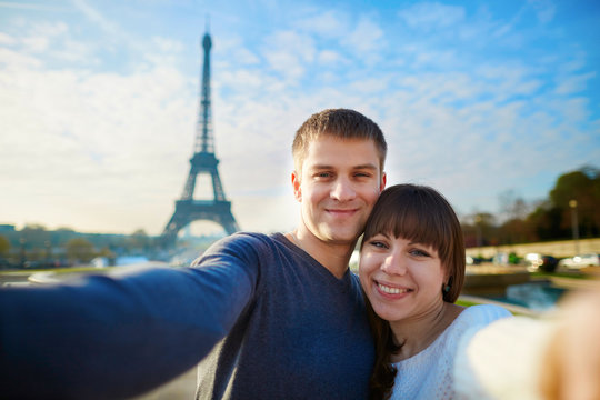 Happy couple of tourists taking selfie in Paris