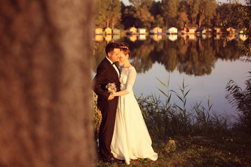 Bridal couple holding each other near lake