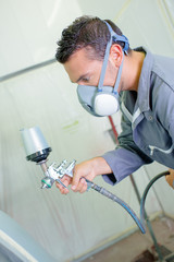 Mechanic spray painting a car