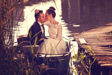 Obraz premium Bride and groom kissing in a boat