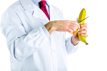 Doctor in white coat cutting a banana with scissors