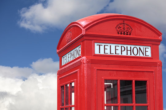 London red telephone box booth isolated against a fluffy clouds blue sky photo