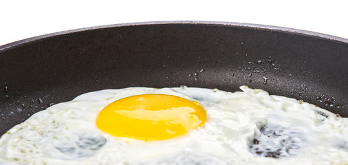 Fried egg in a frying pan over white background