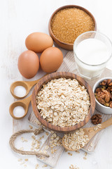 oat flakes and ingredients on a white wooden table, vertical