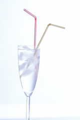 flute com agua gelo e duas palhinhas sobre fundo branco