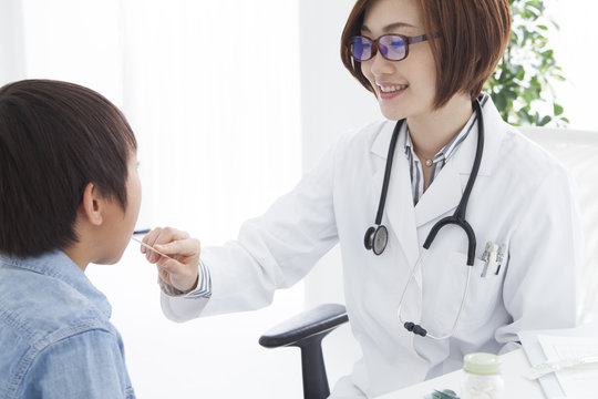 Woman doctor looking at a child's throat