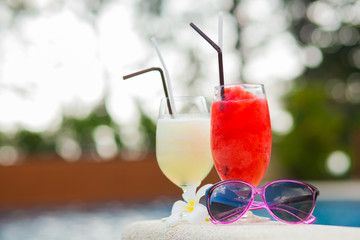 two glasses of cocktails and sunglasses near pool