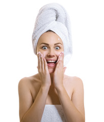 Surprised woman wrapped in a towel applaying cream or moisturize