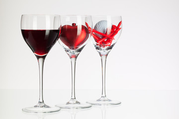 Wine glasses with red wine, heart and golf ball